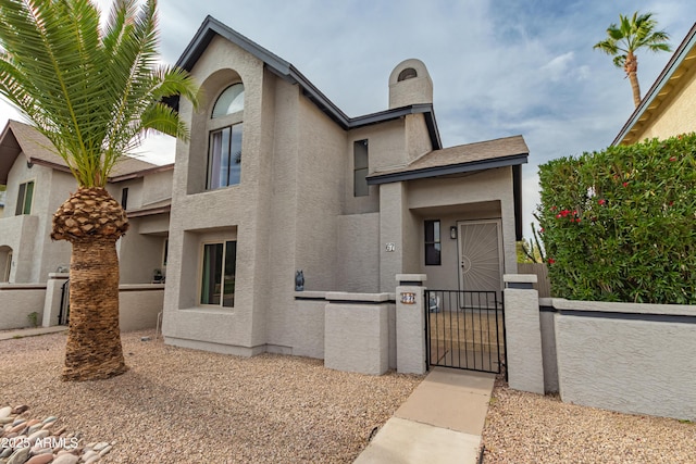view of front of property featuring a gate, a fenced front yard, and stucco siding