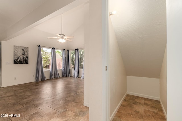 bonus room featuring baseboards, a ceiling fan, stone finish flooring, and lofted ceiling