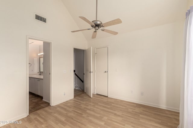 unfurnished bedroom with visible vents, light wood-type flooring, high vaulted ceiling, baseboards, and connected bathroom