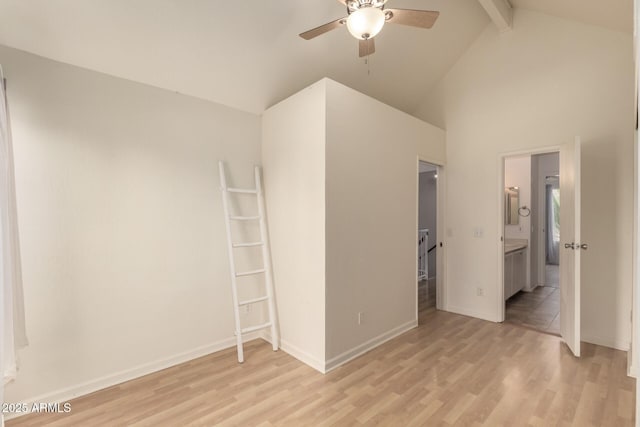 unfurnished bedroom featuring beamed ceiling, light wood-style floors, baseboards, high vaulted ceiling, and connected bathroom