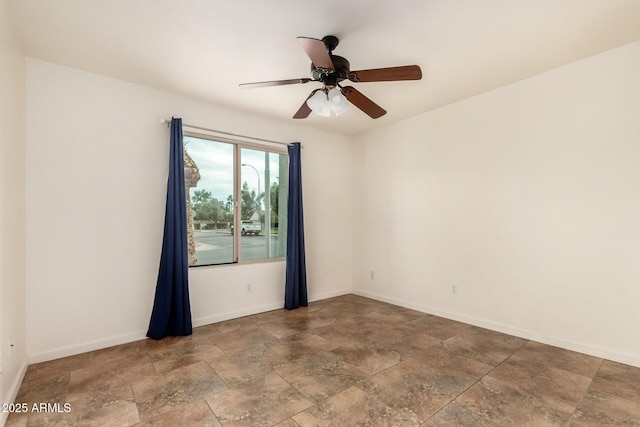 empty room with baseboards, stone finish flooring, and ceiling fan