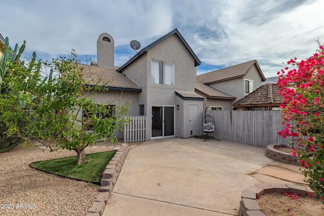 rear view of property featuring a patio, fence, a chimney, and stucco siding