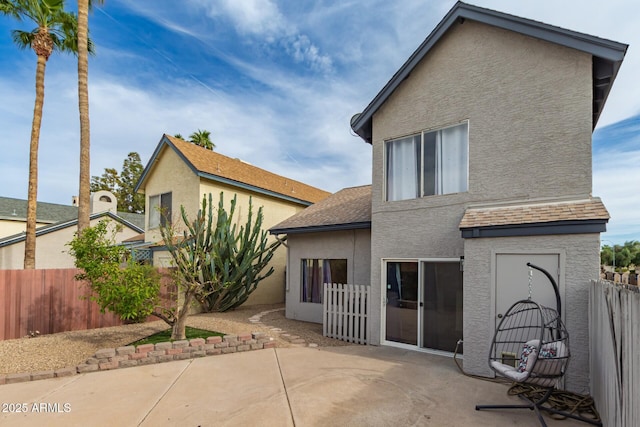 rear view of property with fence, a patio, and stucco siding