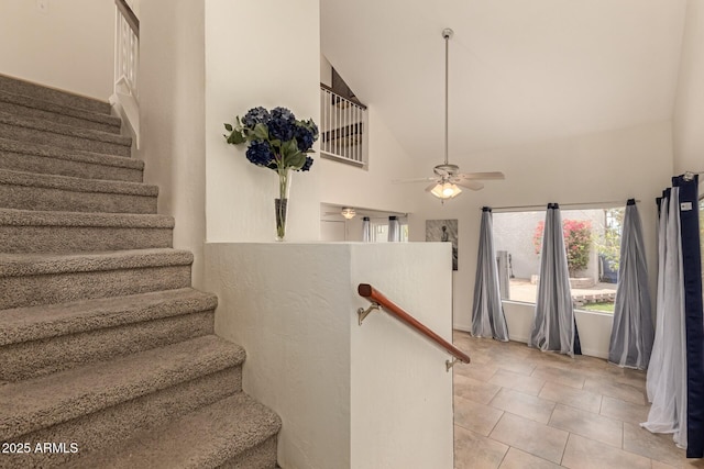 stairway with tile patterned flooring, a ceiling fan, and high vaulted ceiling
