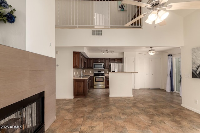 kitchen with ceiling fan, dark brown cabinetry, a towering ceiling, visible vents, and appliances with stainless steel finishes