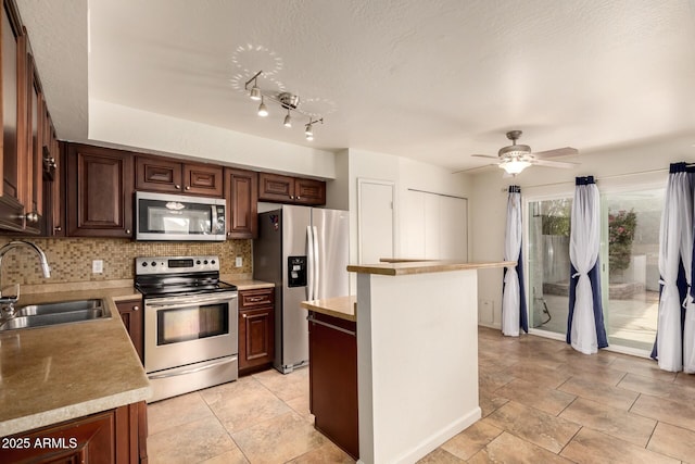 kitchen featuring decorative backsplash, ceiling fan, light countertops, a sink, and stainless steel appliances
