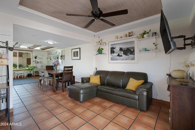 living room with crown molding, tile flooring, ceiling fan, and a tray ceiling