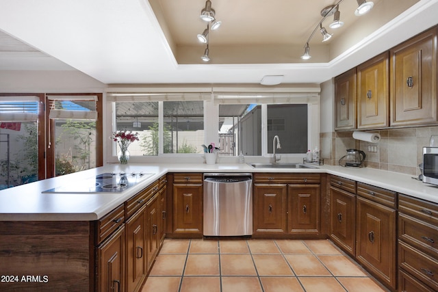 kitchen with dishwasher, track lighting, tasteful backsplash, a tray ceiling, and sink