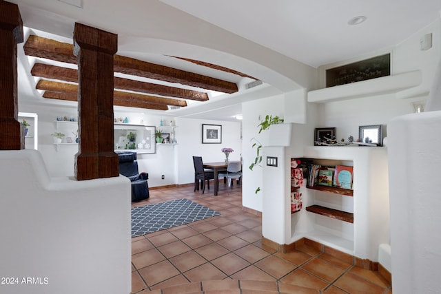 interior space featuring beamed ceiling, ornate columns, and tile floors