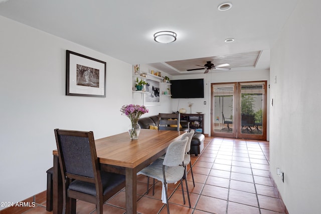 dining room featuring tile flooring, ceiling fan, and a tray ceiling