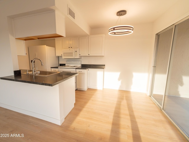 kitchen featuring sink, kitchen peninsula, pendant lighting, white appliances, and white cabinets