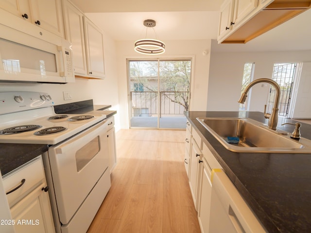 kitchen featuring sink, white appliances, hanging light fixtures, and white cabinets