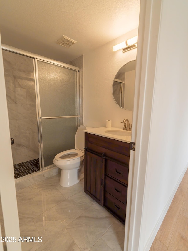 bathroom with vanity, an enclosed shower, a textured ceiling, and toilet