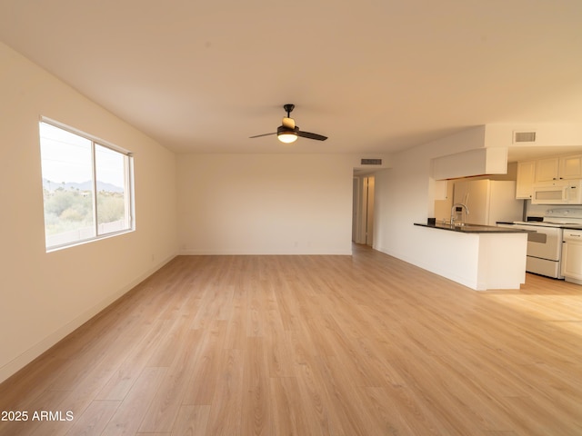 unfurnished living room with ceiling fan, sink, and light hardwood / wood-style floors