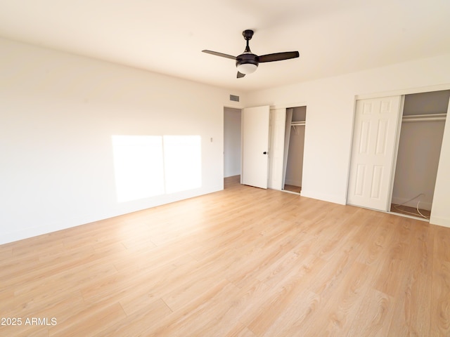 unfurnished bedroom featuring ceiling fan, two closets, and light hardwood / wood-style floors