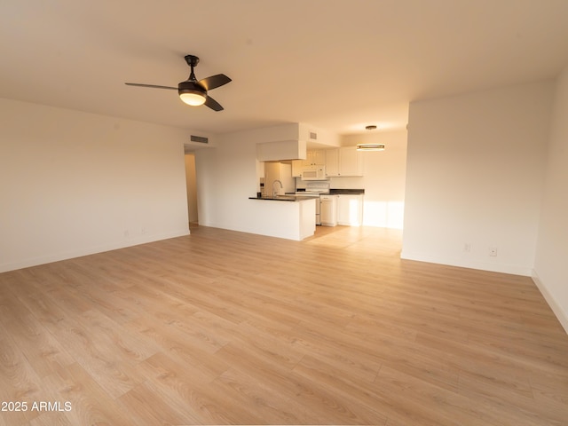 unfurnished living room featuring ceiling fan, sink, and light wood-type flooring