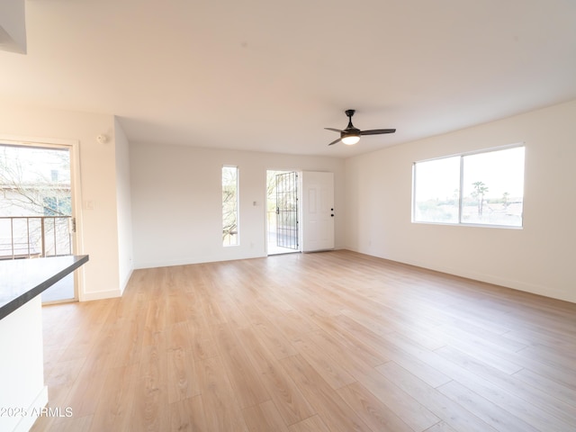 unfurnished living room with ceiling fan, a healthy amount of sunlight, and light wood-type flooring