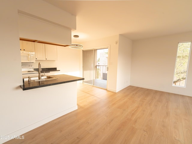 kitchen featuring white cabinetry, sink, pendant lighting, and light hardwood / wood-style floors