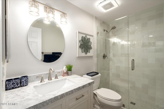 bathroom featuring a shower with shower door, toilet, and vanity