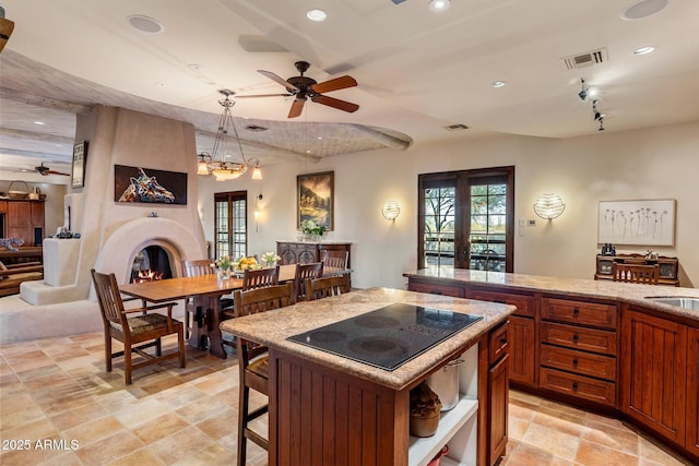 25002 N Quail Haven Dr, Rio Verde, AZ 85263 - kitchen featuring black electric stovetop, ceiling fan, recessed lighting, a large fireplace, and brown cabinets