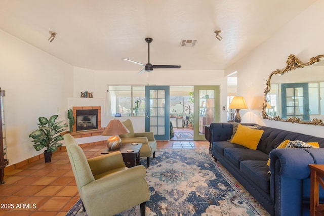 tiled living area featuring visible vents, baseboards, a fireplace, a ceiling fan, and french doors