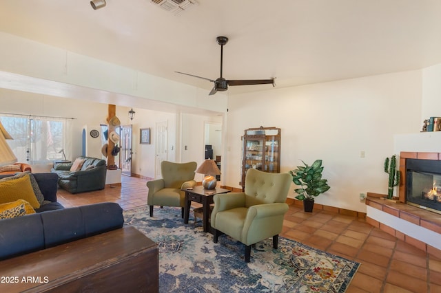 living area featuring a tiled fireplace, tile patterned floors, baseboards, and visible vents