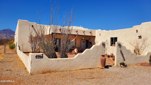 exterior space with a mountain view, a gate, fence, and stucco siding