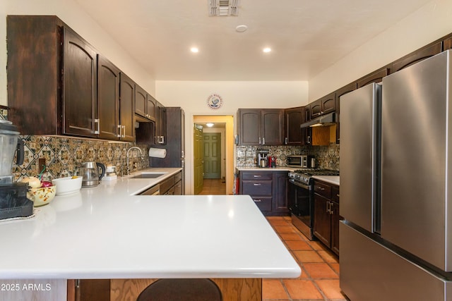 kitchen featuring light countertops, under cabinet range hood, a sink, visible vents, and appliances with stainless steel finishes