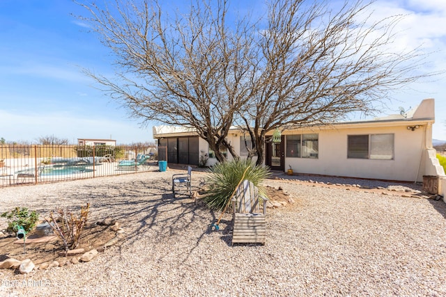 back of property with a fenced in pool, a sunroom, stucco siding, and fence