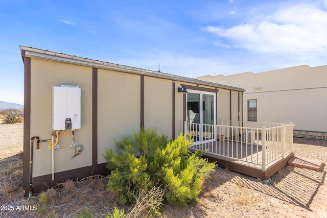 rear view of property featuring stucco siding and tankless water heater