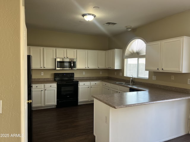 kitchen featuring black range with electric cooktop, a peninsula, a sink, visible vents, and stainless steel microwave