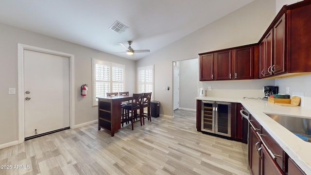 kitchen featuring ceiling fan, lofted ceiling, wine cooler, and light hardwood / wood-style flooring