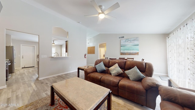 living room with ceiling fan, light hardwood / wood-style flooring, and vaulted ceiling