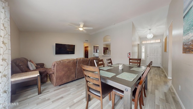 dining space with ceiling fan with notable chandelier and light hardwood / wood-style floors