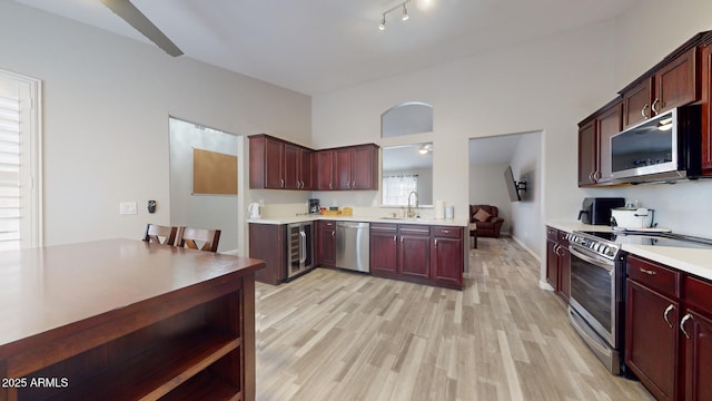 kitchen featuring light wood-type flooring, stainless steel appliances, wine cooler, and sink