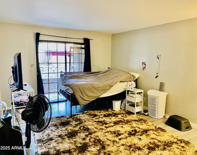 bedroom featuring access to exterior, baseboards, and wood finished floors