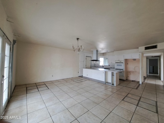 kitchen featuring island exhaust hood, visible vents, double oven, light tile patterned flooring, and a chandelier