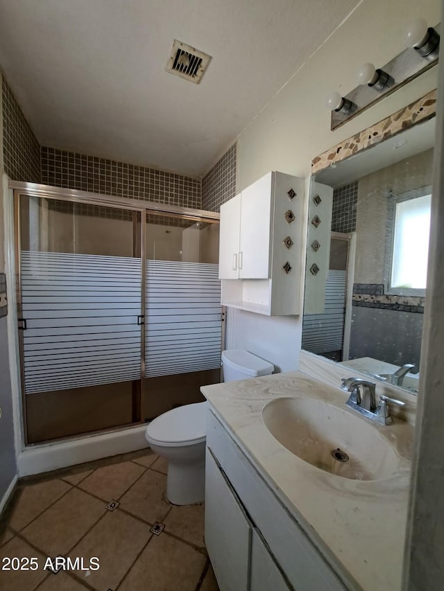 bathroom featuring toilet, a stall shower, tile patterned flooring, and vanity