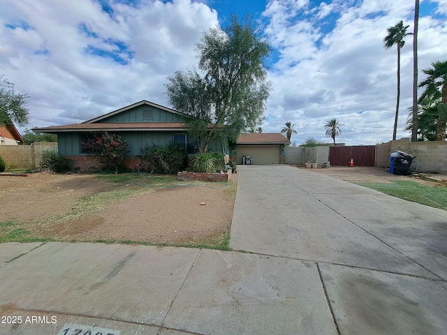 ranch-style home featuring brick siding, board and batten siding, fence, a garage, and driveway