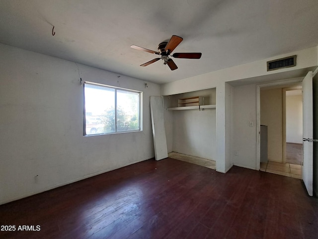 unfurnished bedroom featuring ceiling fan, a closet, visible vents, and wood finished floors