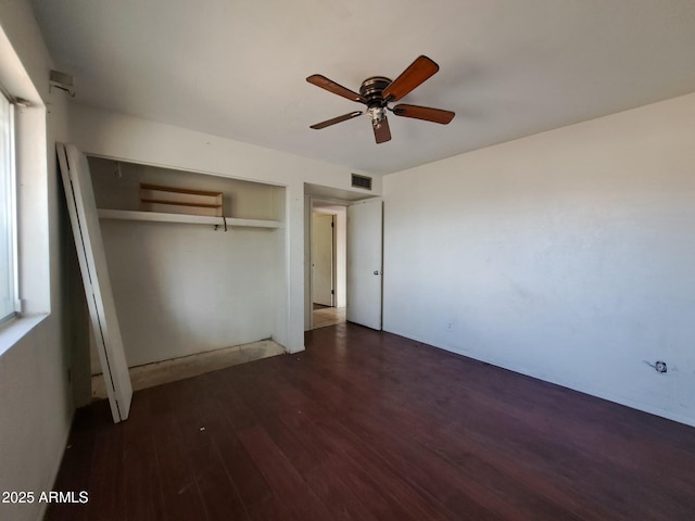 unfurnished bedroom with a closet, visible vents, ceiling fan, and wood finished floors