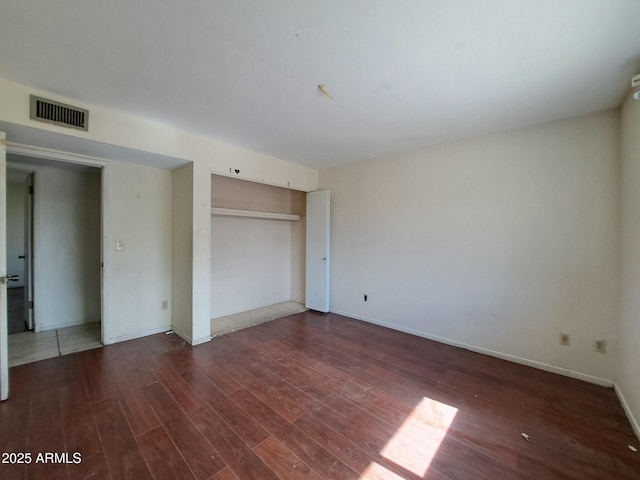 unfurnished bedroom with baseboards, a closet, visible vents, and wood finished floors