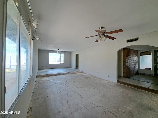 unfurnished room with arched walkways, visible vents, and ceiling fan