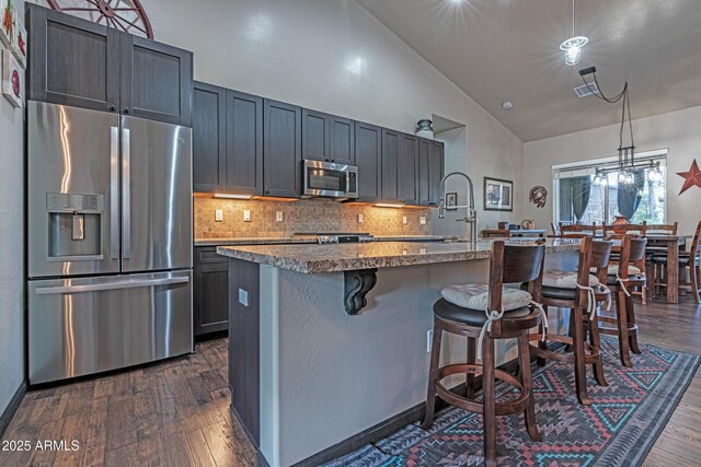 670 S Mountain Pines Ave, Show Low, AZ 85901 - kitchen featuring appliances with stainless steel finishes, a kitchen bar, backsplash, dark wood-style floors, and a kitchen island with sink