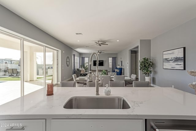 kitchen with light stone counters, sink, and a healthy amount of sunlight