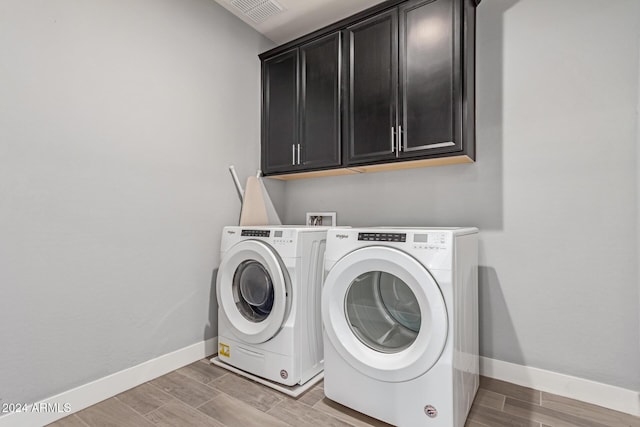 clothes washing area featuring cabinets and washing machine and dryer