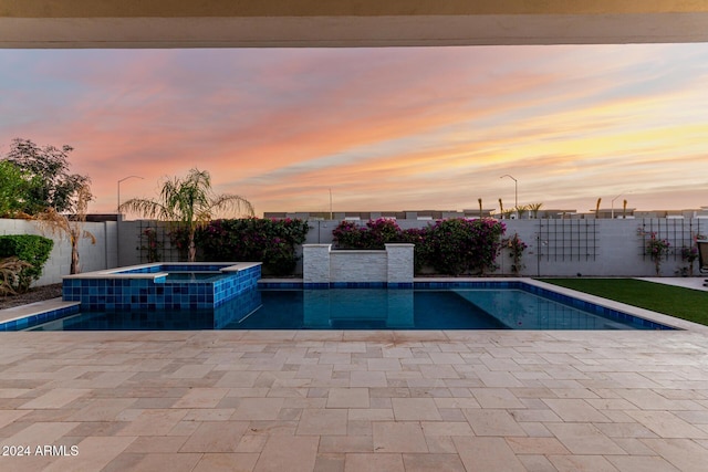 pool at dusk with an in ground hot tub