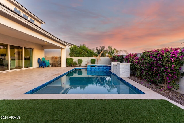 pool at dusk featuring a patio area and an in ground hot tub