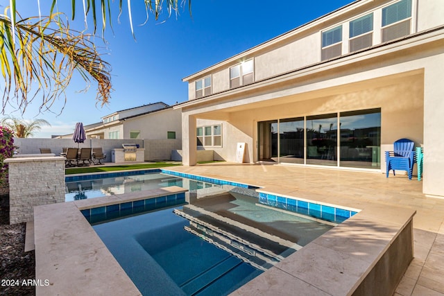 view of swimming pool with an in ground hot tub, a patio, and an outdoor kitchen