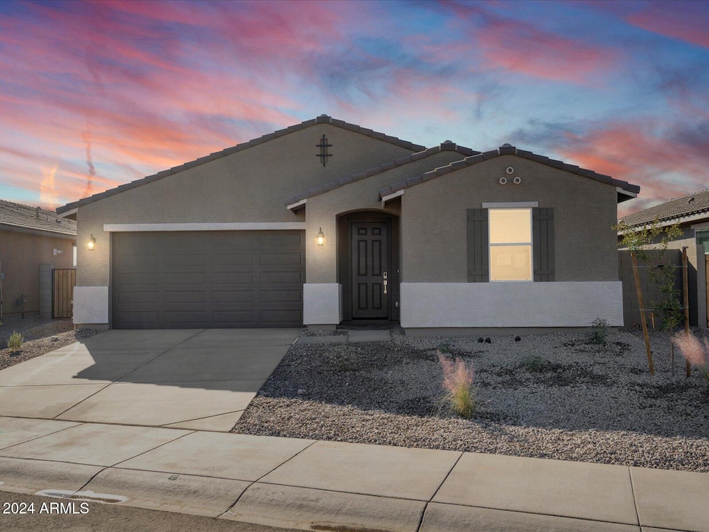 ranch-style house featuring a tiled roof, stucco siding, a garage, and concrete driveway